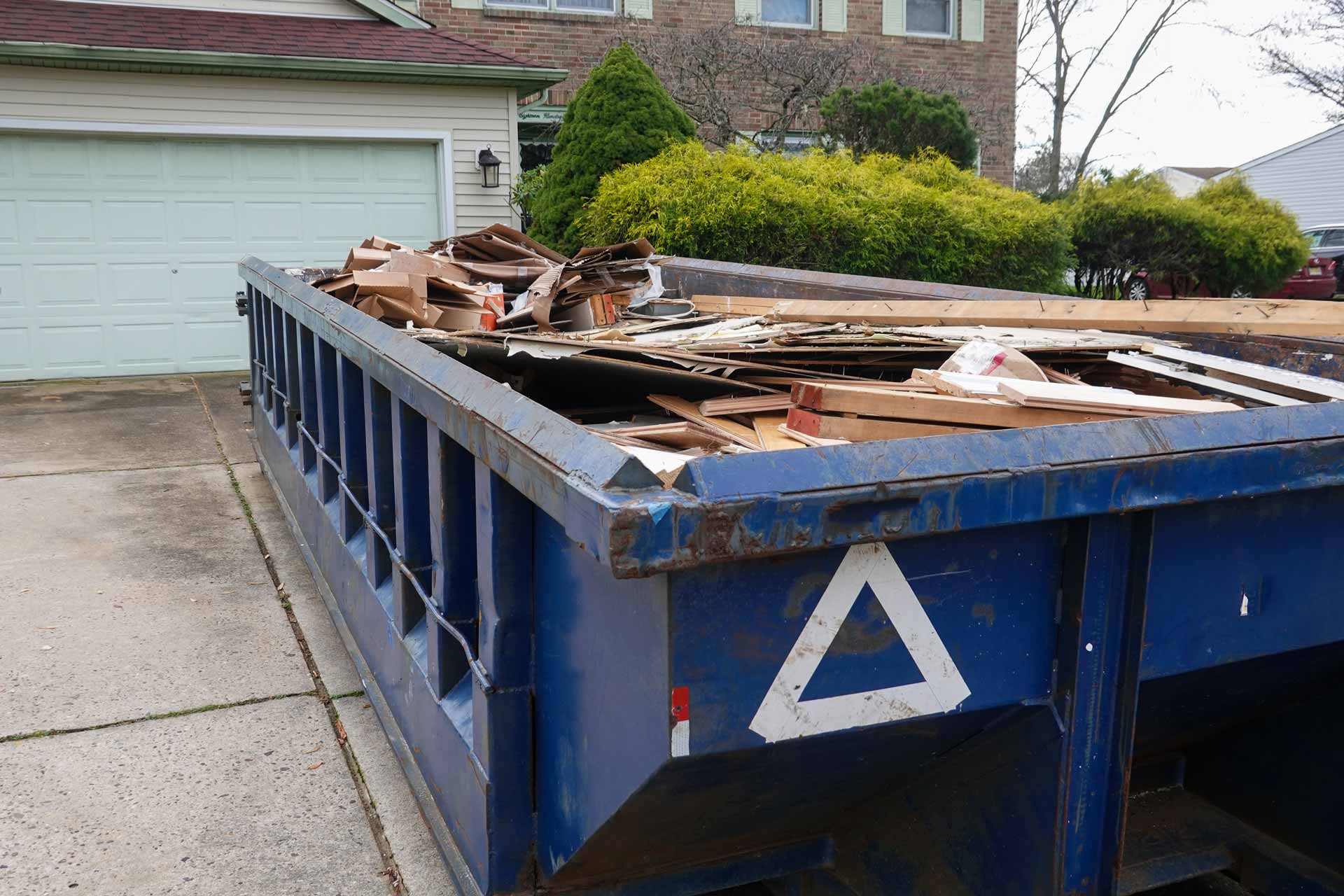 Blue rental dumpster full of construction debris