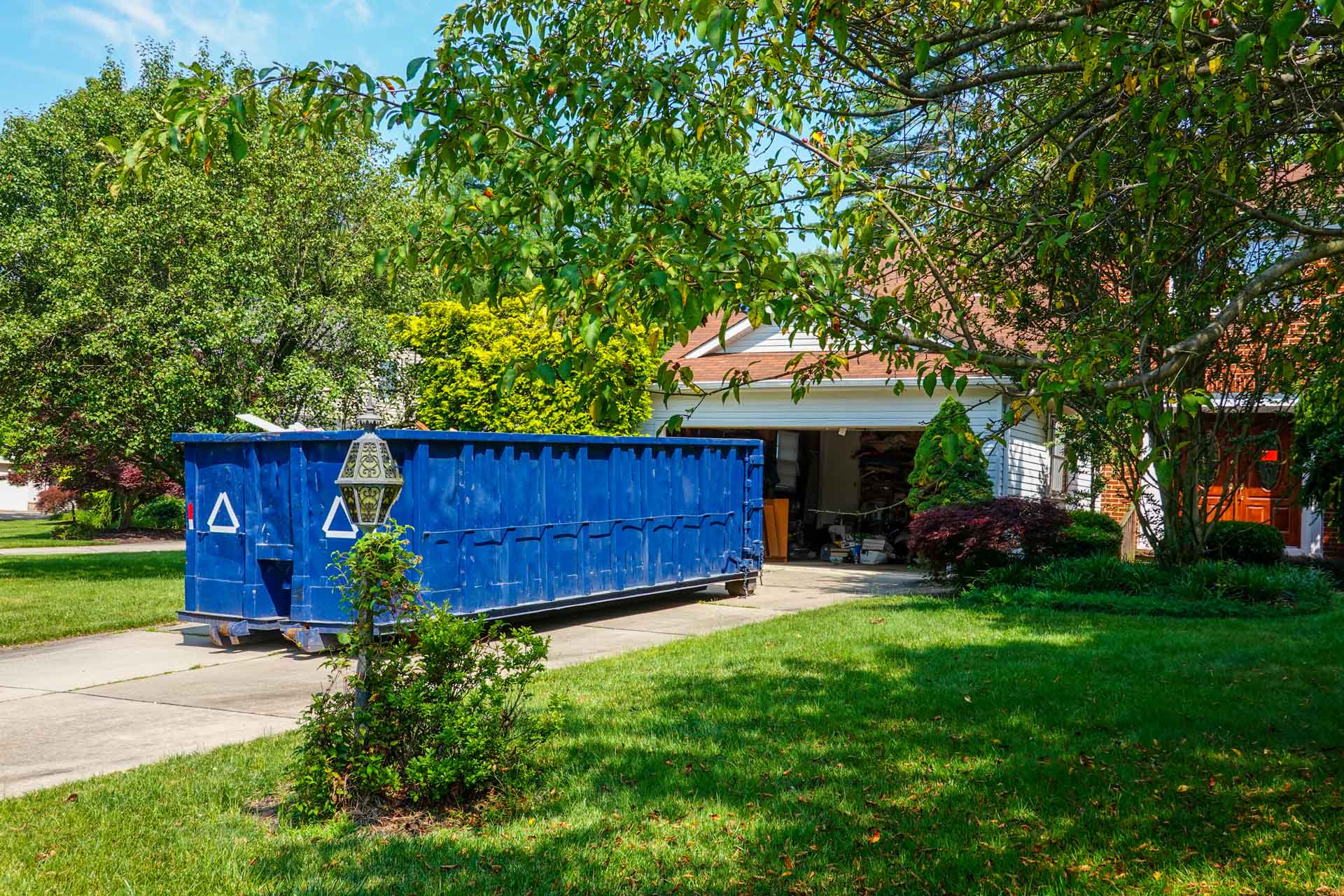 Blue rental dumpster in residential driveway